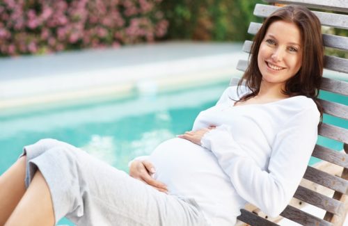Schwangere Frau entspannt am Pool, ideal für Erholung trotz Hämorrhoiden.